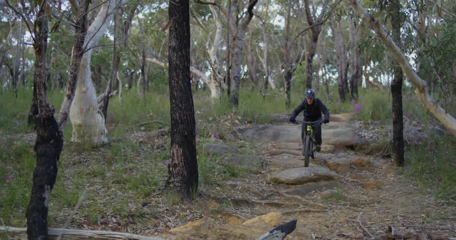 A man rides a mountain bike on a rocky forest trail