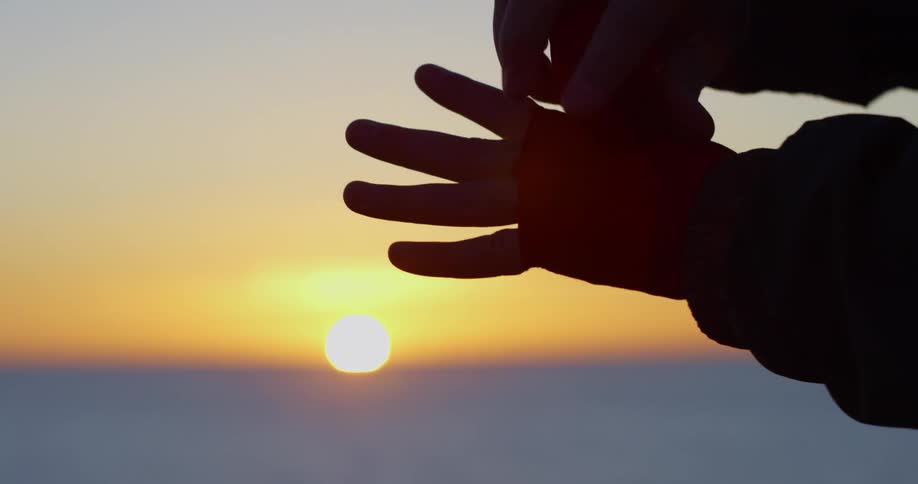 The silhouette of a person wrapping their hand at sunrise on the beach