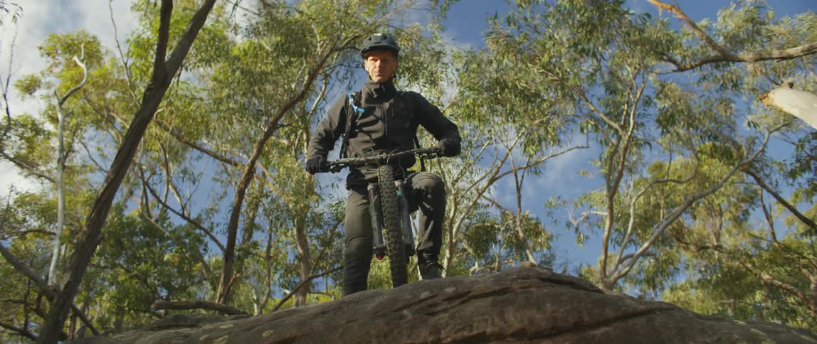 A man rides a mountain bike to a rocky edge and stops