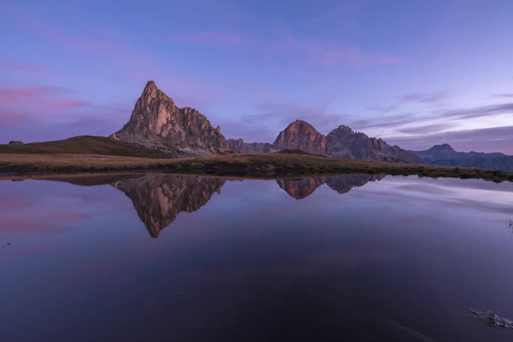 Time lapse photography of a mountain near a lake is displayed at dusk
