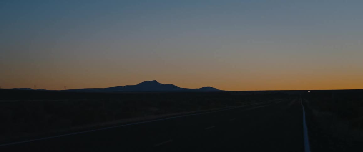 An empty road with mountains on the horizon after the sun has set