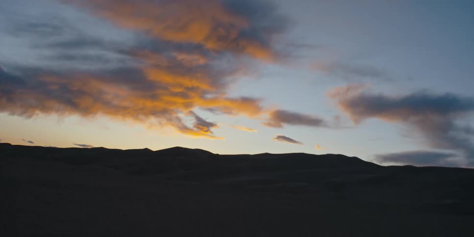Colorful clouds in the sky over a silhouette of sand dunes