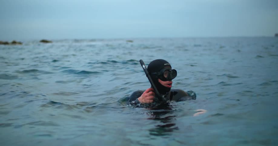 A scuba diver bobbles in the water before putting his breathing apparatus back on