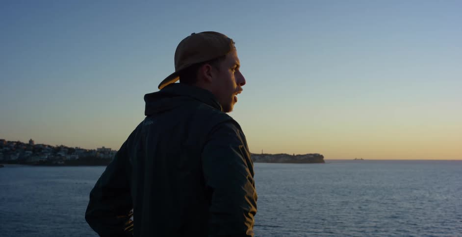 A man is standing by the lake at dusk