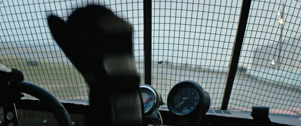 A race car driving raises his hand in the air as he cheers