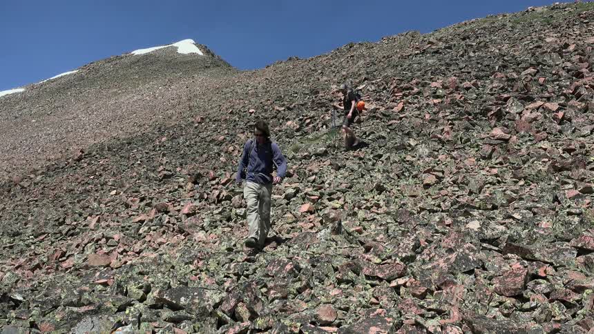 Two people are climbing down rocks