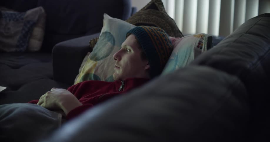 A man is resting on his couch during the day