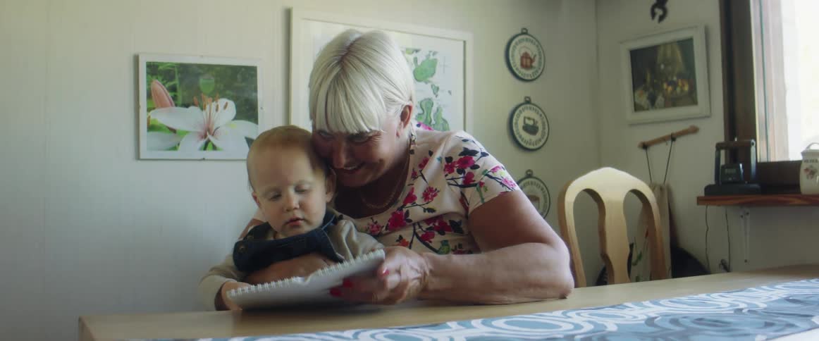 Grandmother showing pictures to her grandson in a room at home