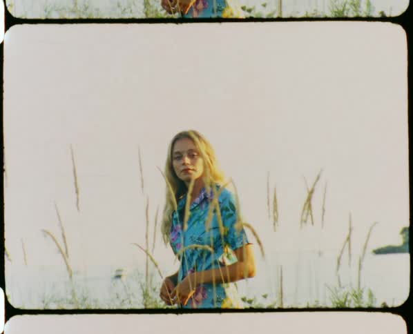 Young blonde woman wearing colorful clothes standing on a field of green grass