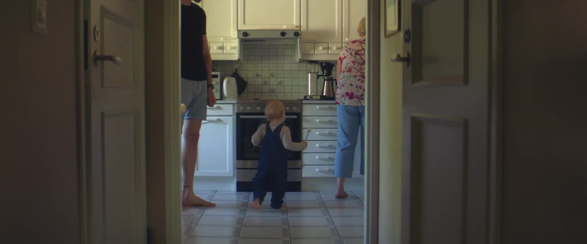 A man a woman and a child in a kitchen with a stove in the background
