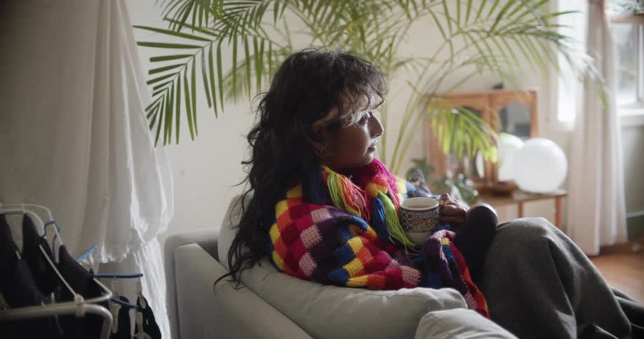 Young woman drinking hot coffee in the couch at home