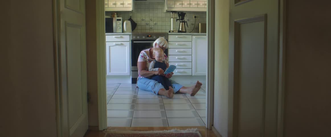 Grandmother playing with her grandson in the kitchen floor