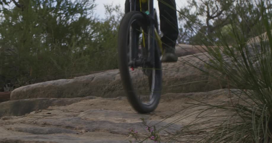 A cyclist rides a mountain bike down a stone slope in the wilderness during the day