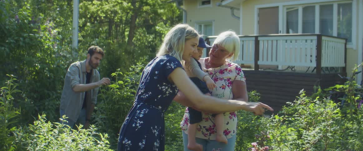A family stands outside a house looking at the plants