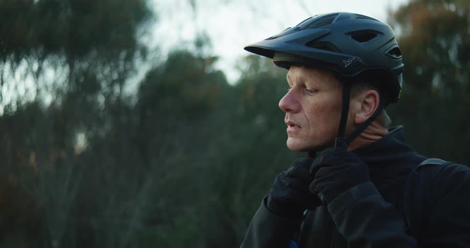 A mature man is preparing to ride a motorbike outdoors in the early morning