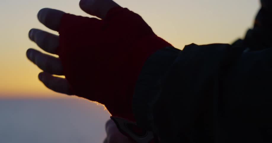 A person wraps a long bandage around their hand near the ocean