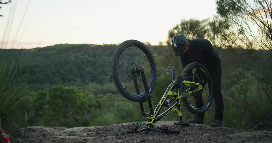 A man has his bicycle upside down as he works on one of the tires