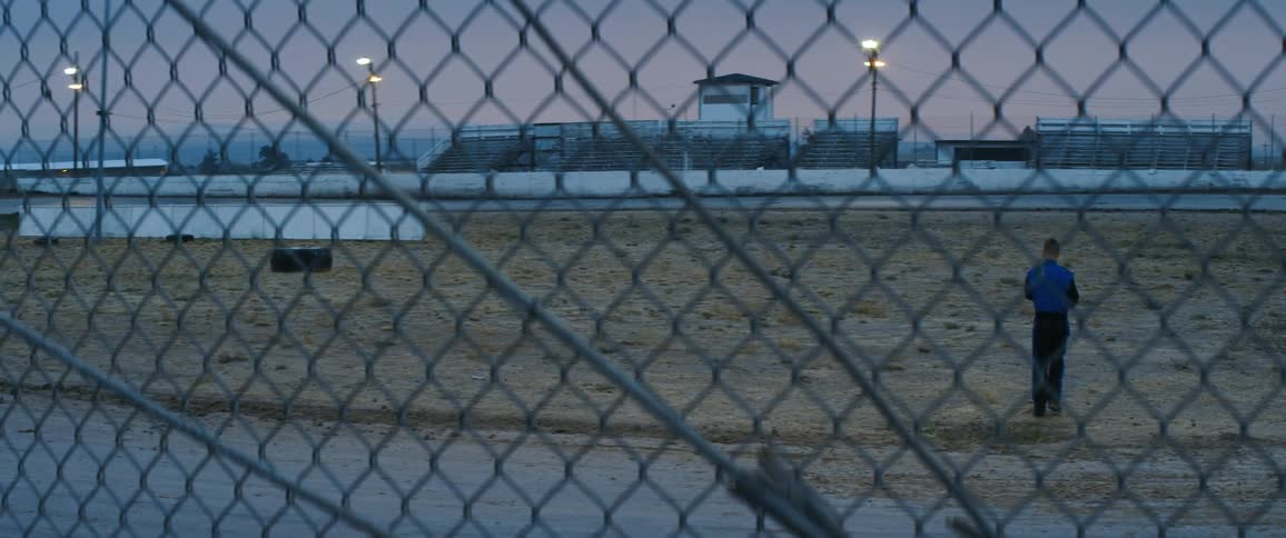 Man walking on a race track angrily throws someting on the ground at sunset