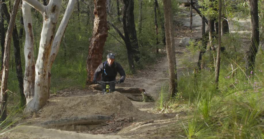 Man rides mountain bicycle along trail taking a jump