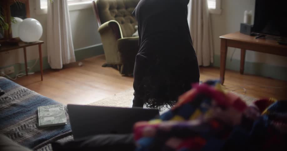 A woman moves into a downward dog pose while doing yoga in her living room