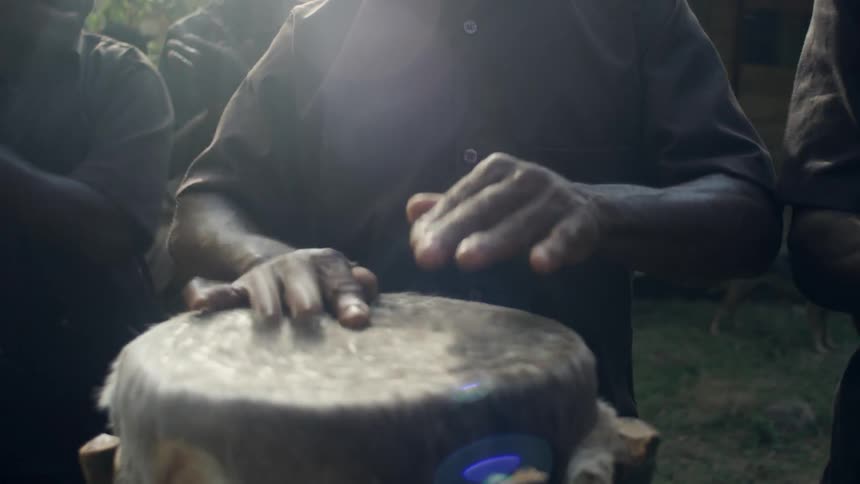 A man is playing a drum while people clap