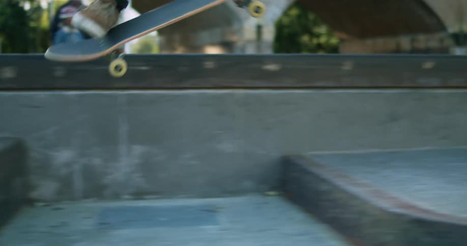 A skateboarder jumps a gap riding in a skate park
