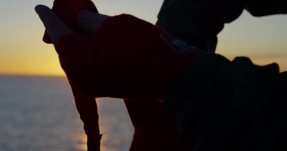 A person wraps their hand with a bandage in front of the ocean