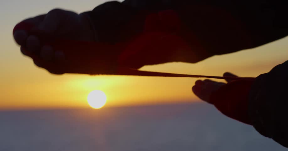 A person wrapping their hands with the sunset the sky and clouds in the background