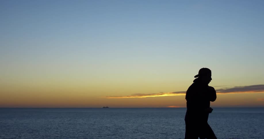 A silhouetted man punching the air outside at dusk