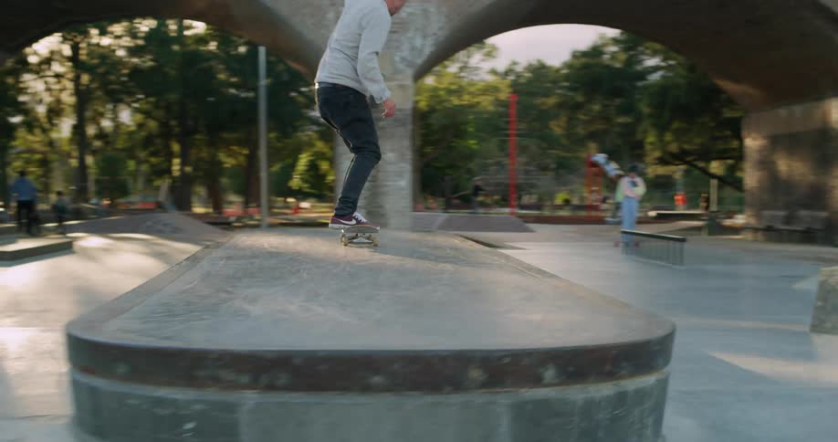 A teenage skateboarder leaps onto a ramp and skates across