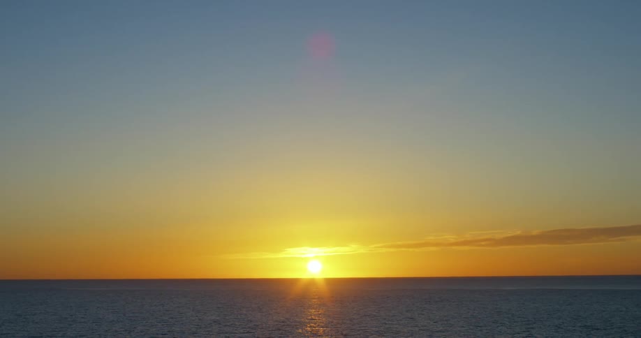 The ocean with rippling water with the sunset the sky and clouds in the background