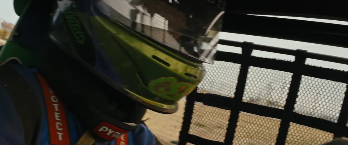 A driver with a helmet driving a race car in the daytime