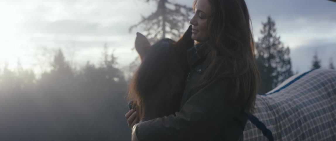 A woman pets her horse outside