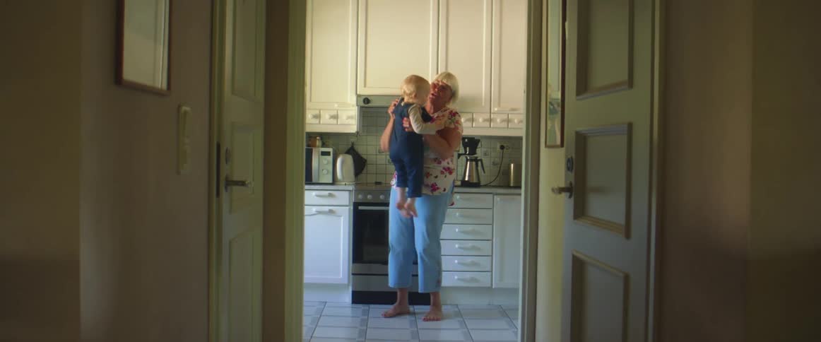 Grandmother holding her grandson in the kitchen at home