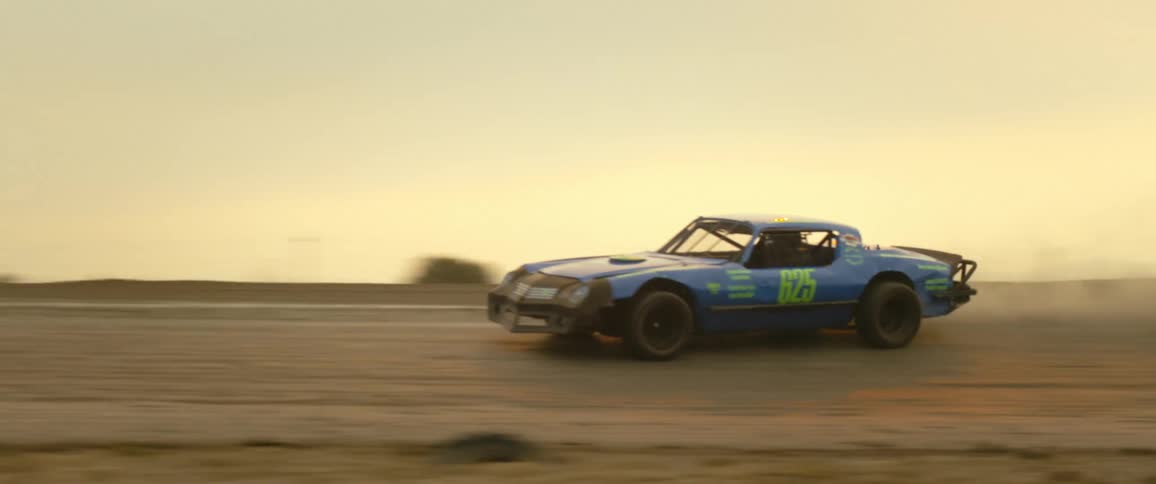 Race car speeds along track sliding and kicking up dust