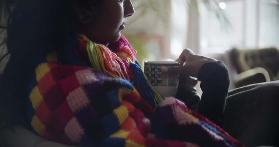 A woman sitting on a couch drinking out of a mug