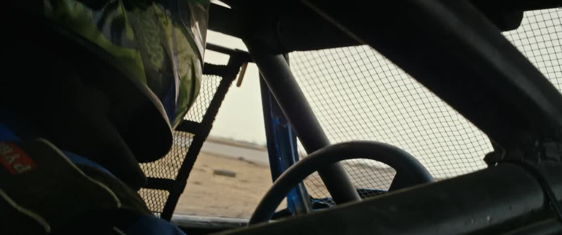 A racer drives a car around a track with a sand infield