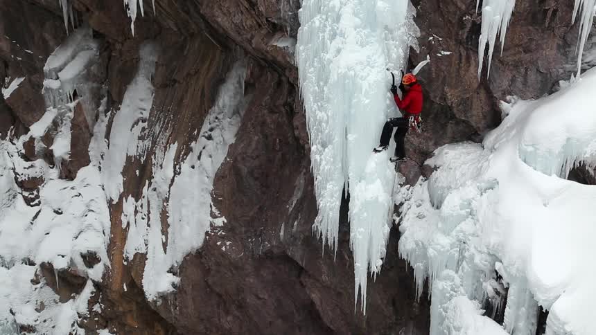 Rock climber using a pick to chip away at ice