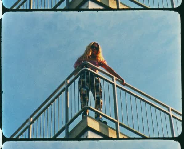 Footage of a woman standing on a bridge is displayed