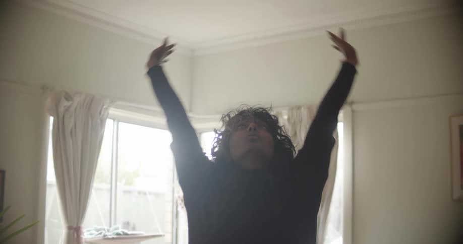A woman stretches high to the ceiling in a meditative yoga pose