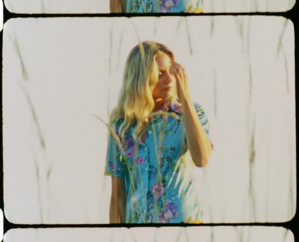 A woman is posing outside in a floral shirt