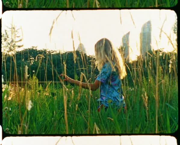 A woman is walking through a grass field