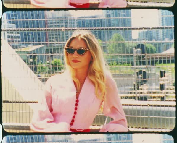A fashionable blonde woman posing in sunglasses with skyscrapers in the distance