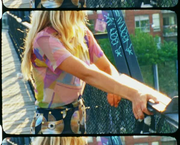 Film footage of a woman standing on a bridge outside of an apartment building