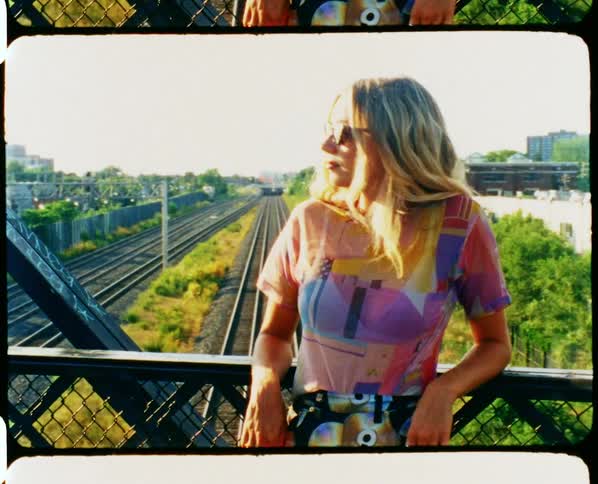 A woman standing and posing on a bridge with skyscrapers in the distance