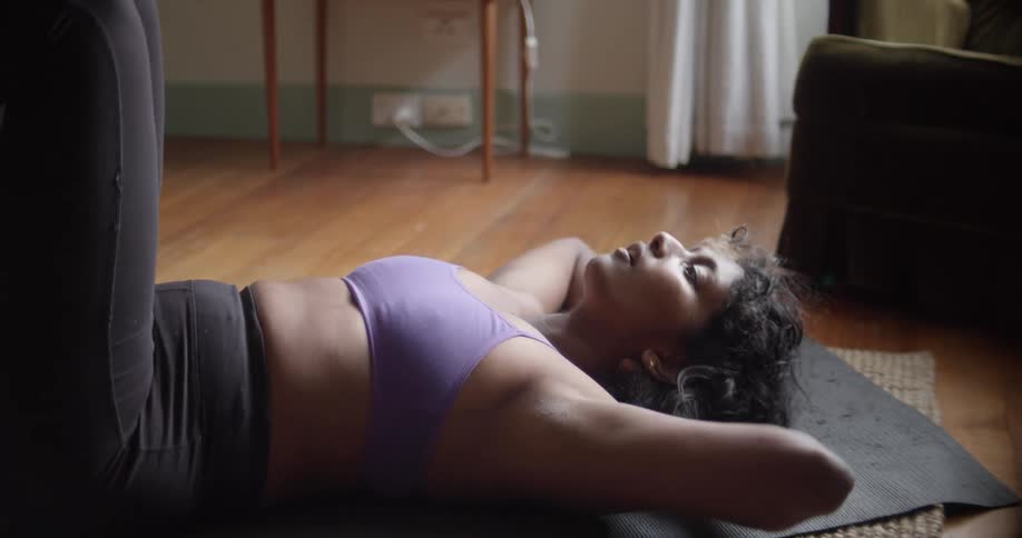 A woman lays on a yoga mat and then moves upward to do a sit up
