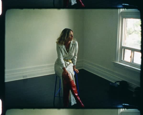 A woman is posing on the stool in the room