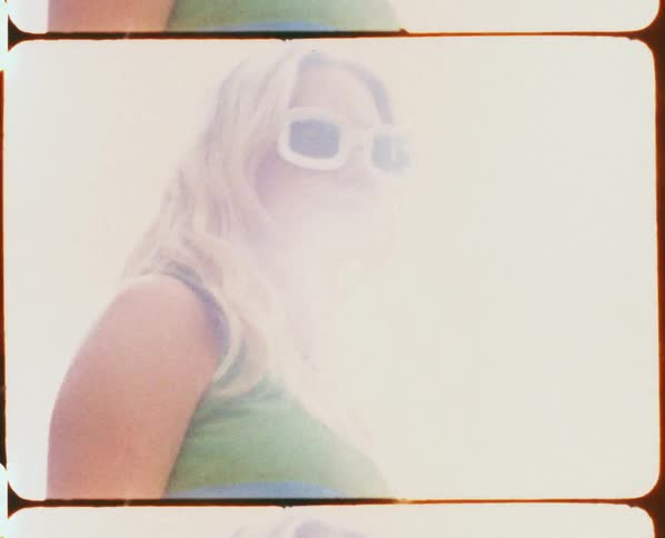 A woman posing outside on a sunny day while wearing white frame sunglasses