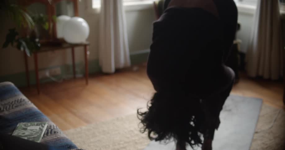 A woman is stretching inside her house during the day