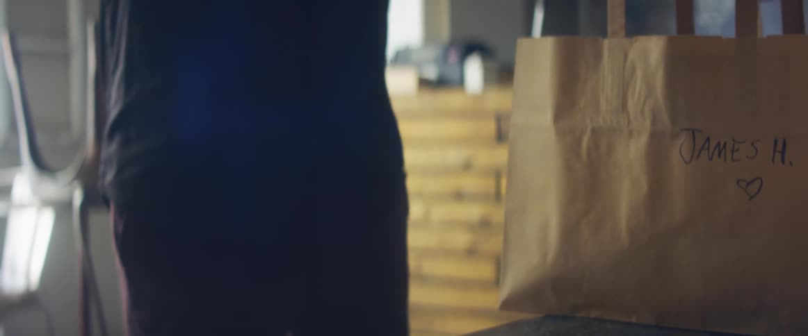 A restaurant employee lifting a paper bag with takeout in a restaurant